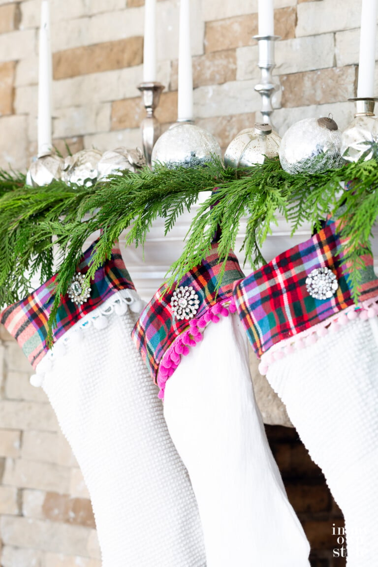 Close up photo of 3 Christmas stockings hanging along cedar trimmed fireplace mantel