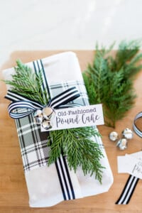 Christmas gift wrapped with white paper and black and white striped ribbon.