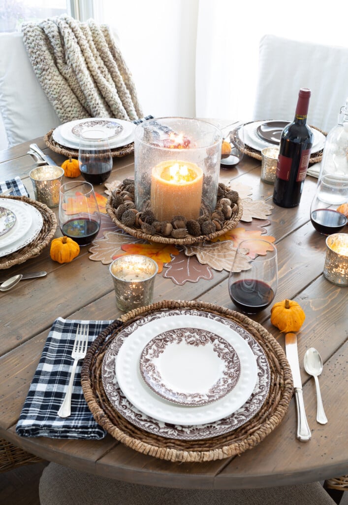 Looking down at a round wood dining table set for Thanksgiving.