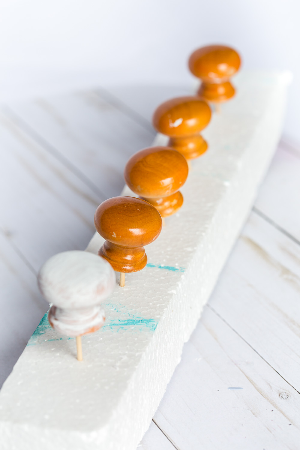 Wood door knobs lined up on toothpicks stuck into foam.