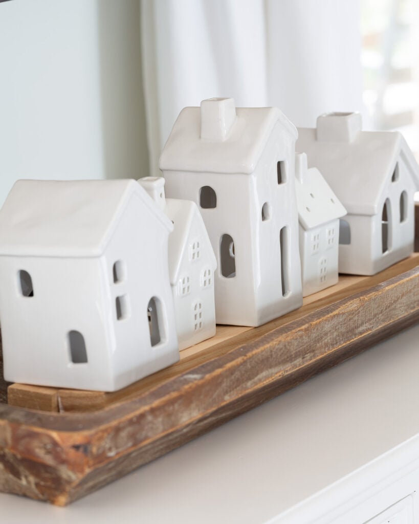 white ceramic tea light houses lined up in a dough bowl on a living room console