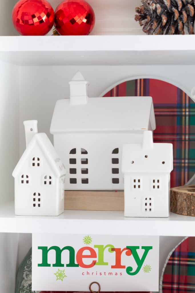 3 white ceramic houses displayed on open shelving in a kitchen.