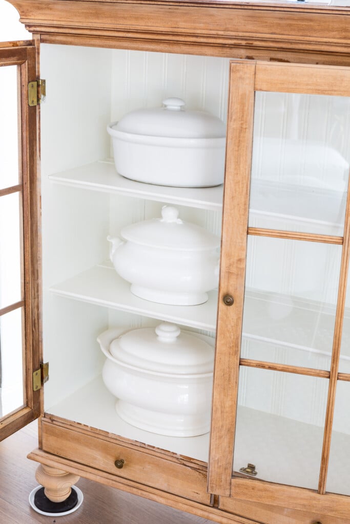 Collection of White serveware in stripped glass fronted cabinet.