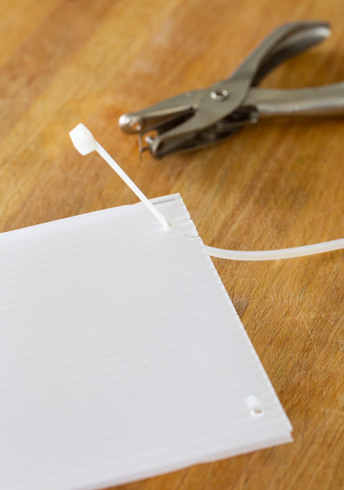 How to attach a zip tie to plastic corrugated sheet to make freezer drawer dividers.