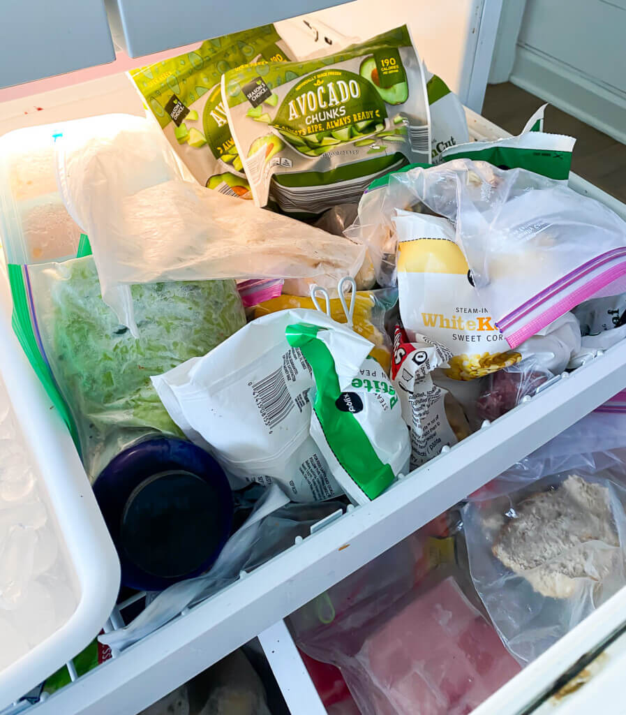 Top slide out drawer on refrigerator with bottom freezer image showing the contents are a mess. Before image.