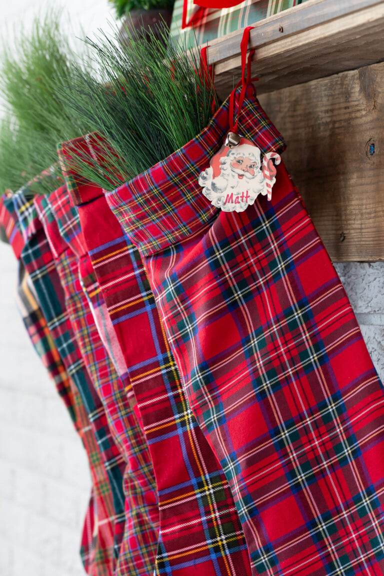 DIY Fabric red plaid handmade stockings hanging from a wood mantel.