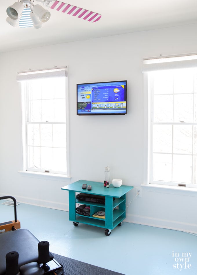 A mounted-flat-screen-TV-on-a-wall in a fitness room with the cords now hidden in wall.