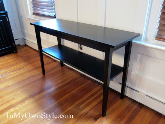 Newly stained black table against a white wall in a dining room.