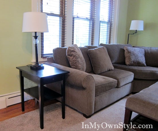 After shot of living room makeover showing black stained table next to a light brown sofa.