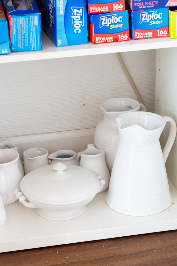 White pitchers being stored in a Butler's pantry cabinet.