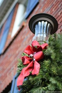 Outdoor Christmas greenery and red bow on porch light