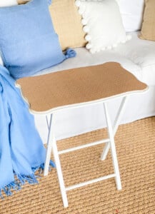 A tray table with a top covered with wicker pattern wallpaper.