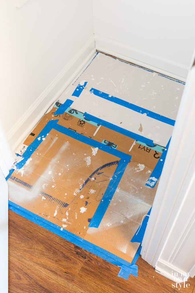 Broken down cardboard boxes taped together on floor of closet used as a drop cloth that doesn't move.